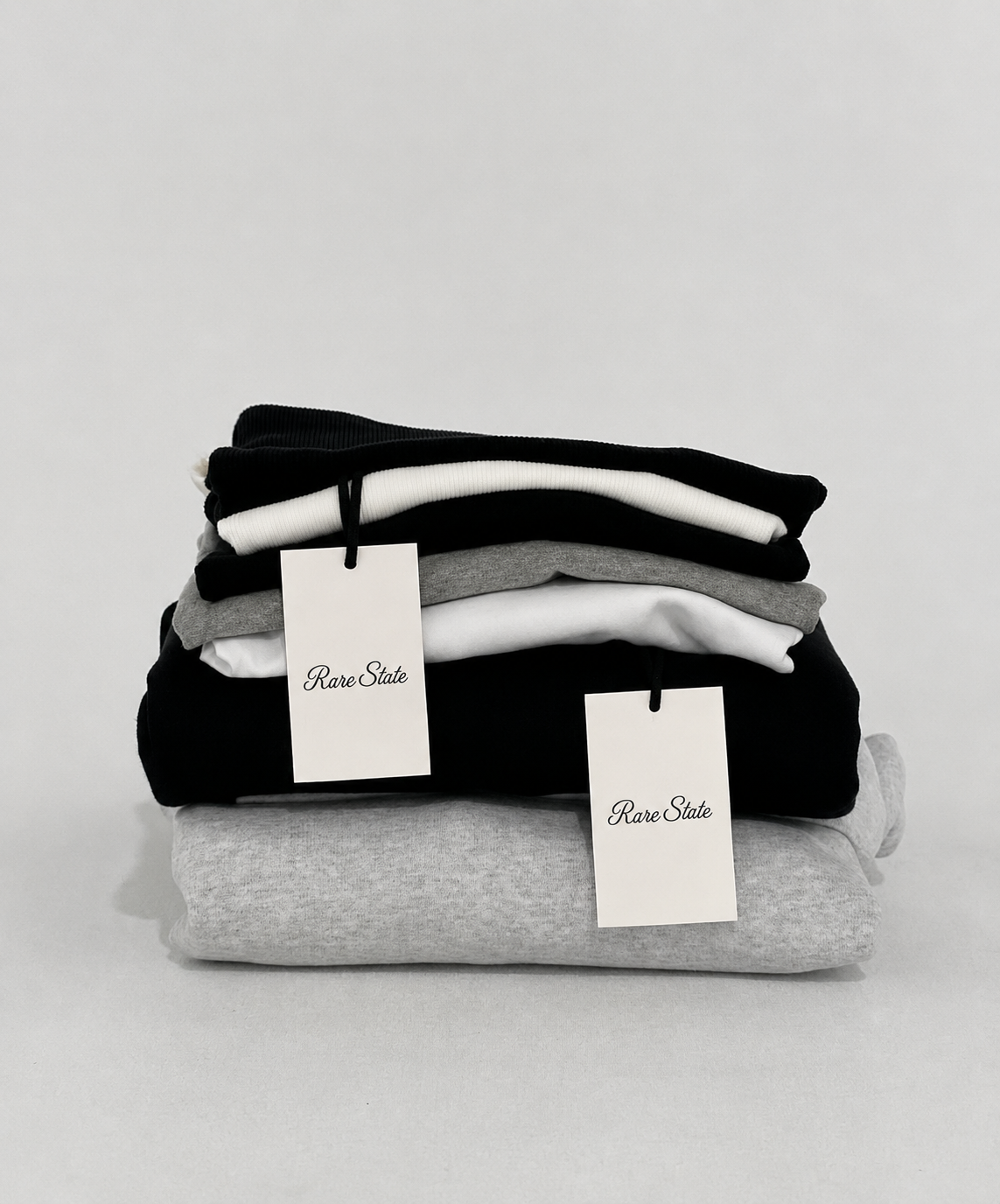 A stack of folded Rare State garments with branded swing tags